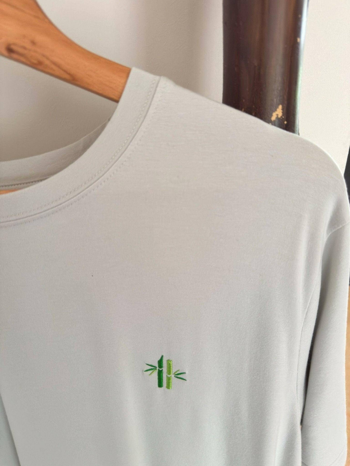 Close up of crew neck of an oyster mushroom bamboo shirt with bamboo logo hanging on a hanger