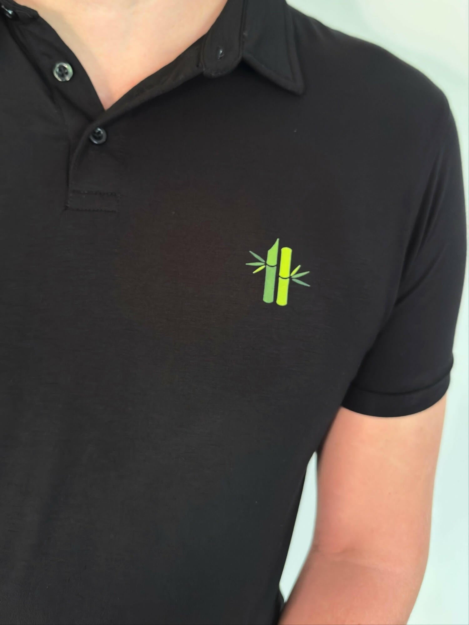 Close up of of bamboo embroidery and collar on model wearing an Athletic Bamboo Polo in black - Robumi Lifestyle