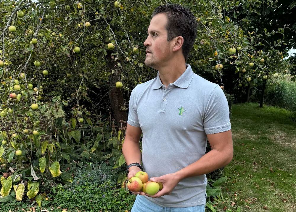 Man in the garden with apples in his hands wearing a Robumi gey bamboo polo