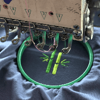 Embroidery of bamboo logo on shirt by an embroidery machine